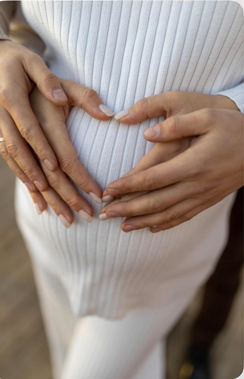 Hands forming a heart on a pregnant belly — gentle perinatal and relationship support